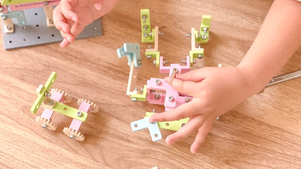 子どもがネジでブロックを組み立てている。